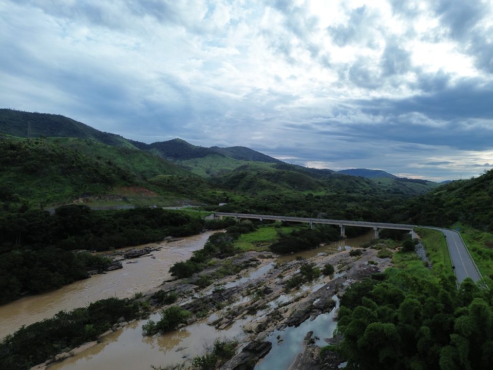 Ponte rodoviária sobre o rio com águas barrentas e céu de nuvens carregadas