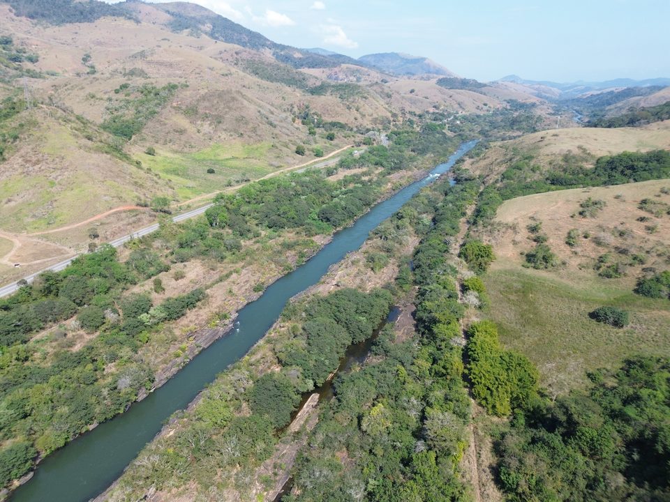 Rio e rodovia lado a lado em um vale de morros