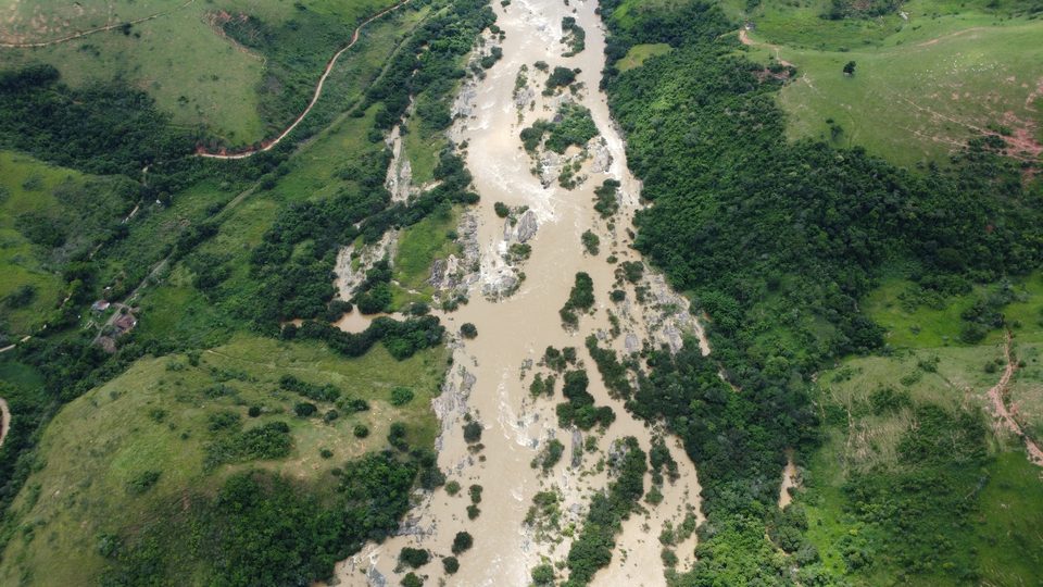 Rio em cheia com águas barrentas se dividindo entre afloramentos rochosos e ilhas de vegetação